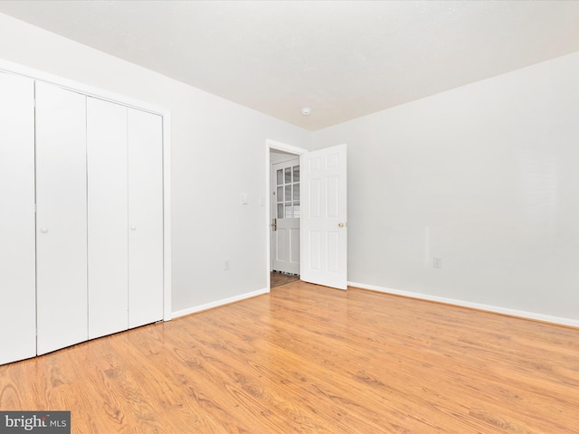 unfurnished bedroom featuring baseboards, a closet, and light wood-style floors