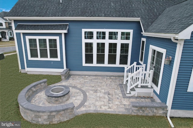 exterior space featuring a fire pit, a yard, and a shingled roof