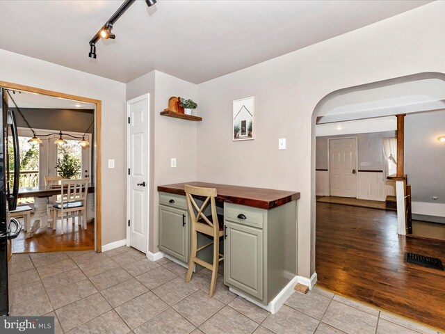 interior space featuring baseboards, arched walkways, light tile patterned flooring, and track lighting