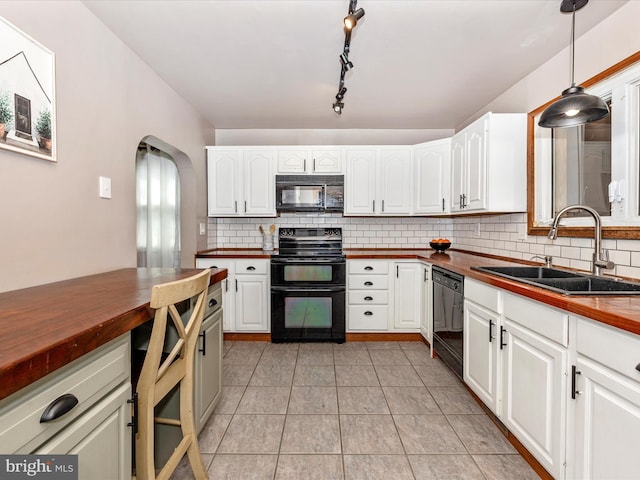 kitchen featuring a sink, arched walkways, butcher block countertops, and black appliances