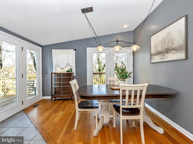 dining area with light wood finished floors, visible vents, baseboards, and lofted ceiling