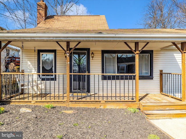 property entrance with covered porch and a chimney