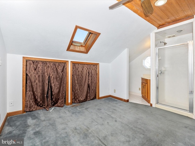 additional living space with ceiling fan, baseboards, carpet floors, vaulted ceiling with skylight, and wooden ceiling