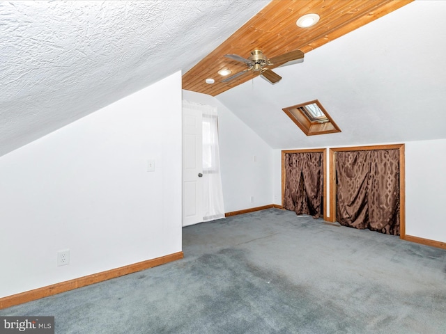 bonus room with vaulted ceiling with skylight, baseboards, a textured ceiling, and carpet flooring