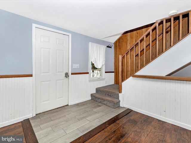 entrance foyer with stairway, wood finished floors, and wainscoting