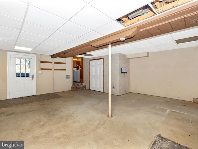 below grade area with a paneled ceiling, concrete block wall, and water heater