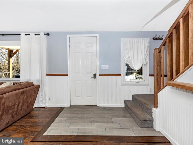 entrance foyer with a wealth of natural light, stairway, and wainscoting