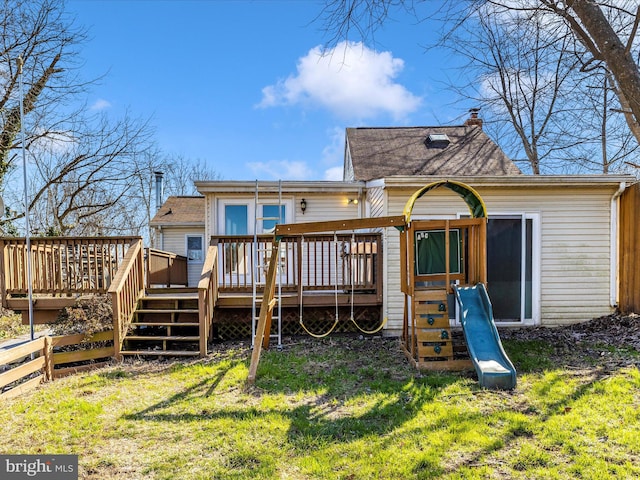 back of property featuring a chimney, a lawn, a wooden deck, and fence