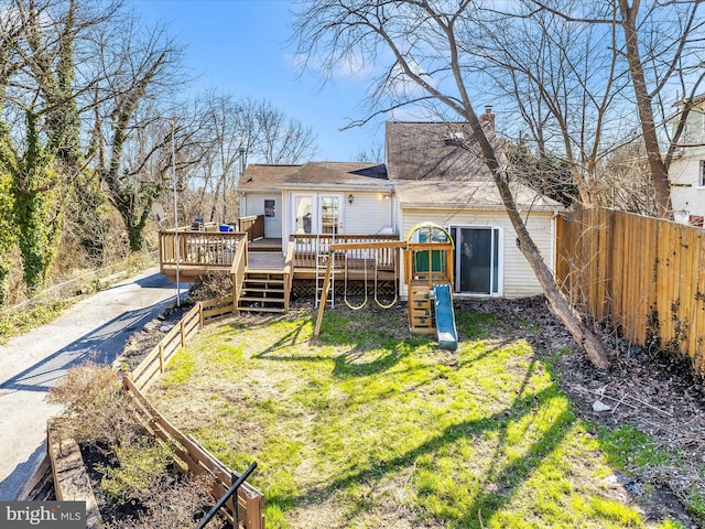 rear view of house featuring a wooden deck, fence private yard, a chimney, a yard, and driveway