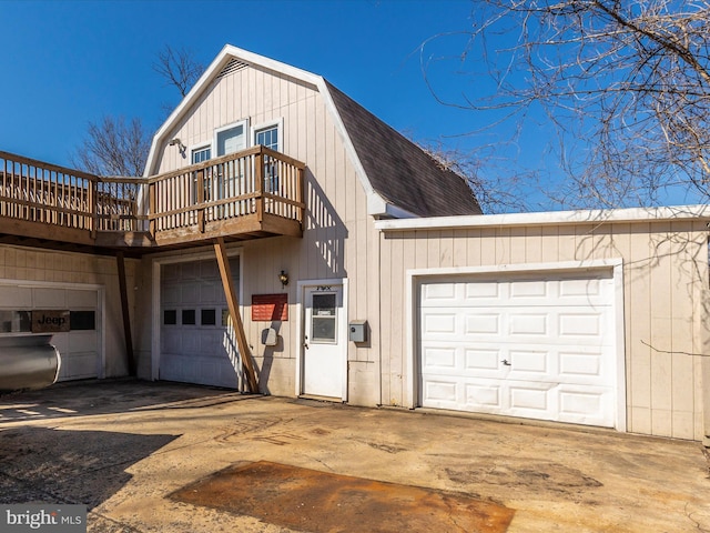 exterior space with concrete driveway, a gambrel roof, and roof with shingles