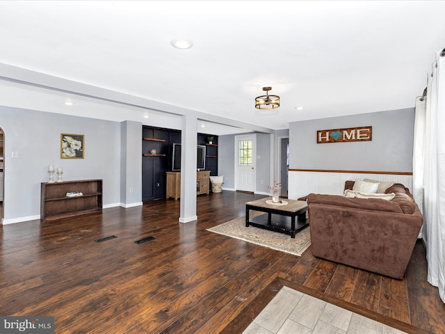 living area with visible vents, wood finished floors, recessed lighting, arched walkways, and baseboards