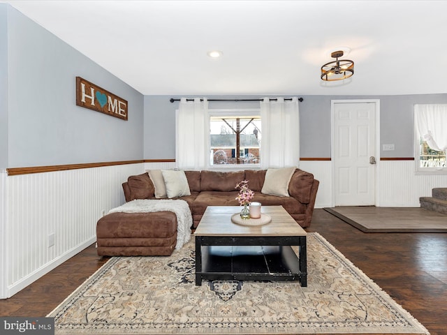 living area with a wainscoted wall, wood finished floors, and stairs