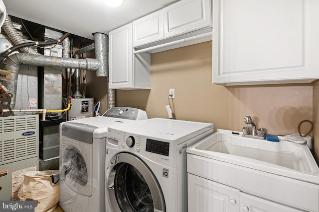 laundry area featuring gas water heater, cabinet space, a sink, and washing machine and clothes dryer