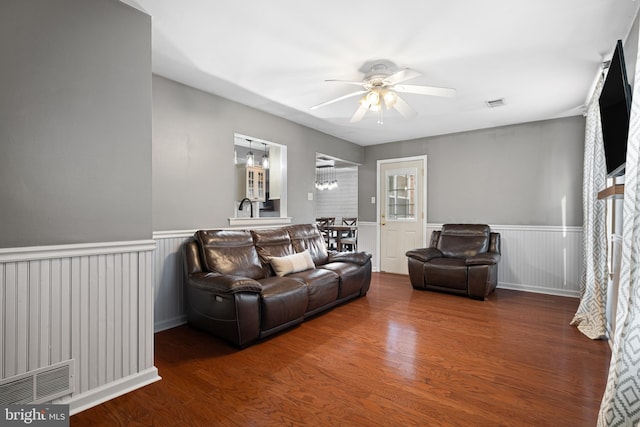 living room featuring visible vents, a wainscoted wall, wood finished floors, and a ceiling fan