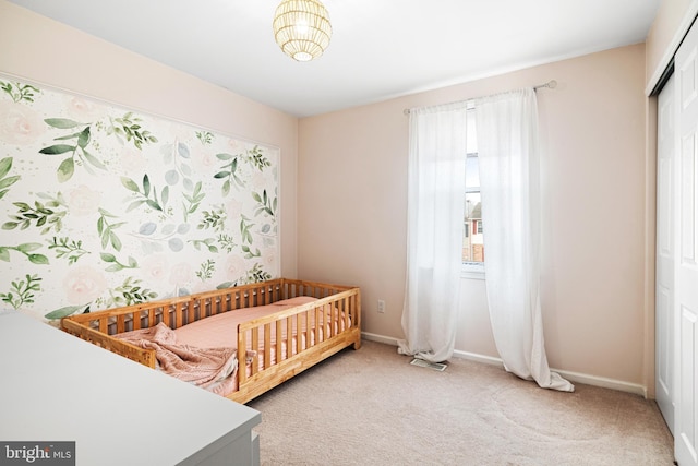 bedroom with a closet, visible vents, light colored carpet, and baseboards