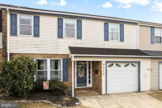 townhome / multi-family property featuring brick siding, an attached garage, and driveway