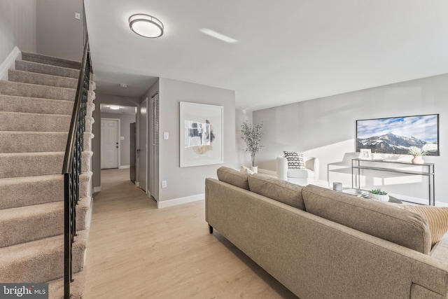 living room with light wood-style flooring, stairway, and baseboards