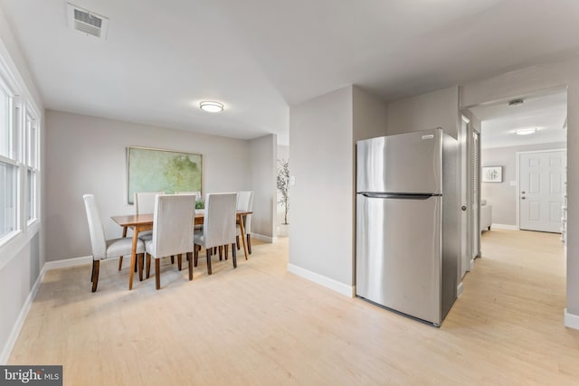 dining area featuring baseboards, visible vents, and light wood finished floors