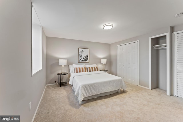 carpeted bedroom featuring two closets and baseboards