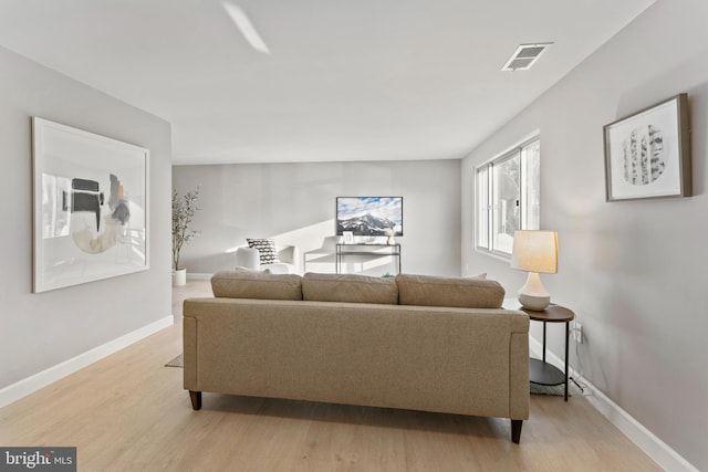 living room featuring light wood-style flooring, visible vents, and baseboards