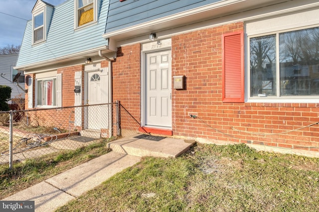 doorway to property featuring brick siding and fence