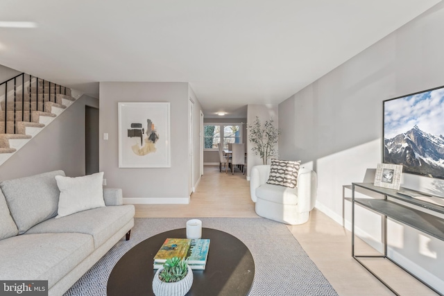 living room featuring stairway, baseboards, and wood finished floors