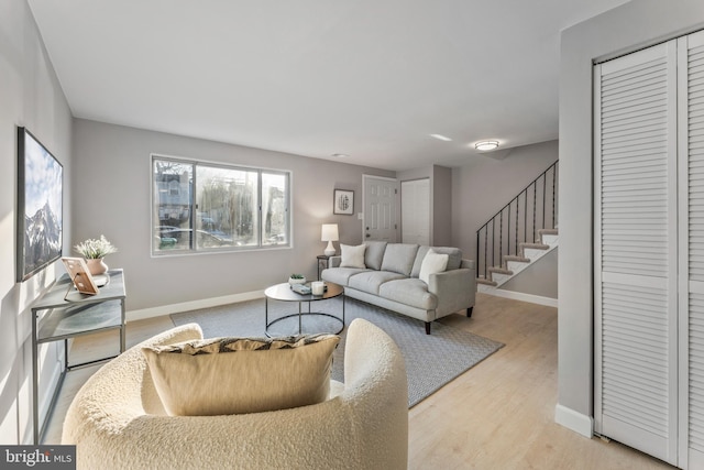 living area with stairway, wood finished floors, and baseboards