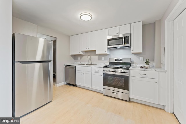 kitchen with light wood-style floors, white cabinetry, stainless steel appliances, and a sink