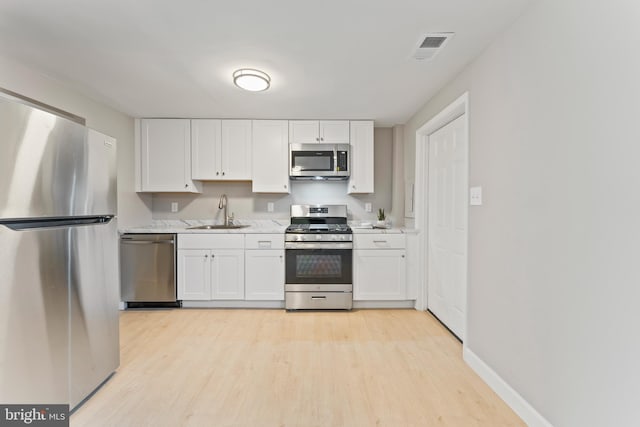 kitchen with light wood-style flooring, stainless steel appliances, a sink, visible vents, and light countertops