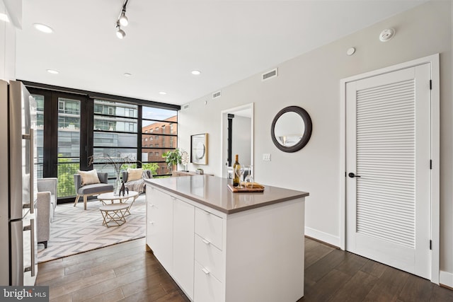 kitchen featuring visible vents, dark wood finished floors, a kitchen island, freestanding refrigerator, and a wall of windows