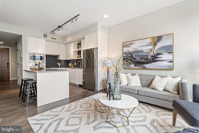 living room with dark wood-style floors, visible vents, and recessed lighting