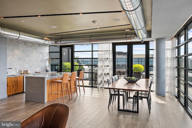 dining area with floor to ceiling windows and wood finished floors