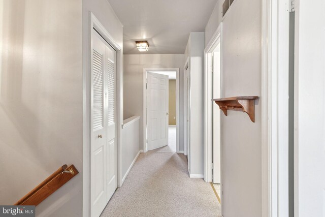 corridor with baseboards and light carpet