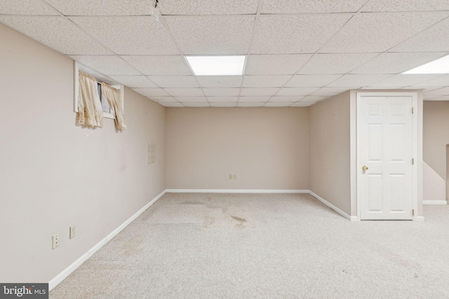 finished basement with a paneled ceiling, baseboards, and carpet floors