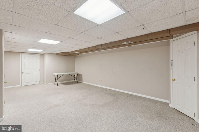 finished below grade area with visible vents, baseboards, a paneled ceiling, and carpet