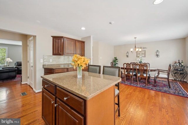 1593 Jason Dr, Cinnaminson, NJ 08077 - kitchen featuring light wood-type flooring, a kitchen bar, light stone counters, a kitchen island, and a chandelier