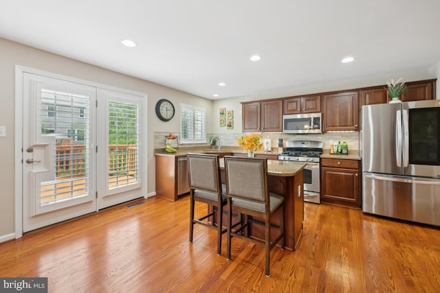 1593 Jason Dr, Cinnaminson, NJ 08077 - kitchen featuring stainless steel appliances, a sink, wood finished floors, a breakfast bar, and decorative backsplash