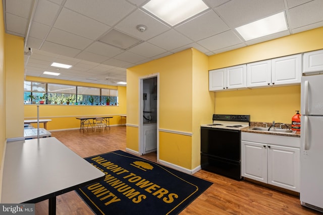 kitchen featuring electric range, light wood-style floors, freestanding refrigerator, white cabinets, and a sink