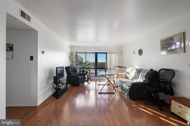 living area with hardwood / wood-style floors, visible vents, and baseboards