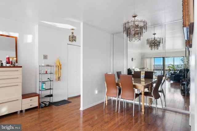 dining area featuring a notable chandelier, baseboards, and wood finished floors