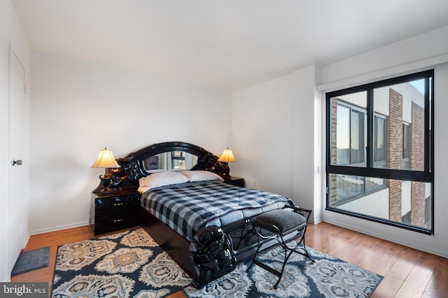 bedroom featuring access to exterior, baseboards, and wood finished floors