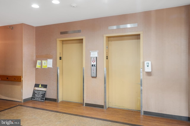 interior space featuring elevator, wood finished floors, and recessed lighting