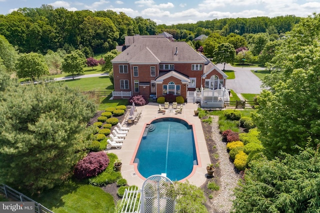 outdoor pool with stairway, fence, and a patio