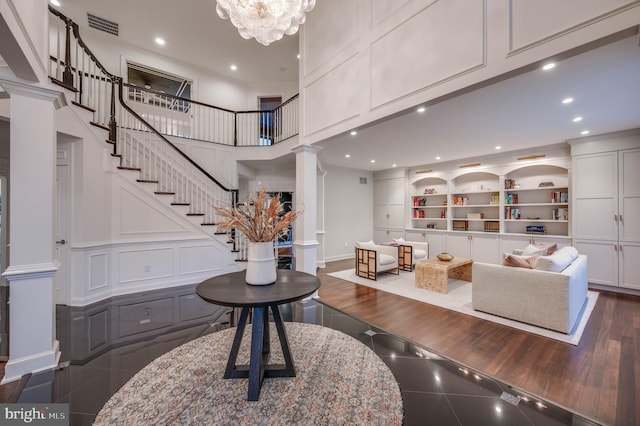 foyer entrance with decorative columns, visible vents, a towering ceiling, a decorative wall, and recessed lighting