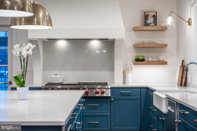 kitchen with stainless steel gas cooktop, a sink, light countertops, blue cabinetry, and decorative backsplash