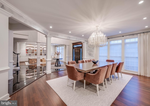 dining space with dark wood-style flooring, an inviting chandelier, decorative columns, and crown molding