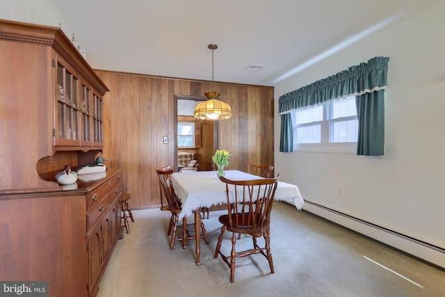 dining area with light carpet, wood walls, a baseboard radiator, and visible vents