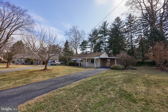 view of front of property featuring driveway, a carport, a chimney, and a front yard