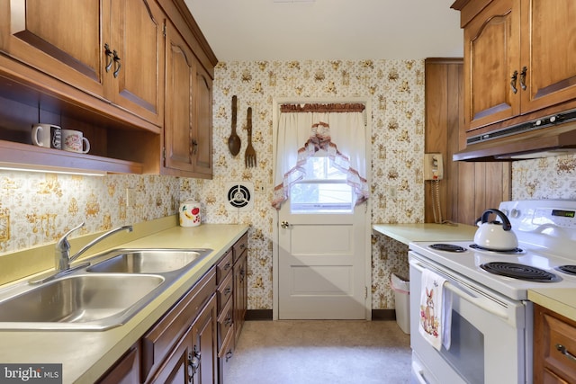 kitchen featuring wallpapered walls, electric range, light countertops, under cabinet range hood, and a sink