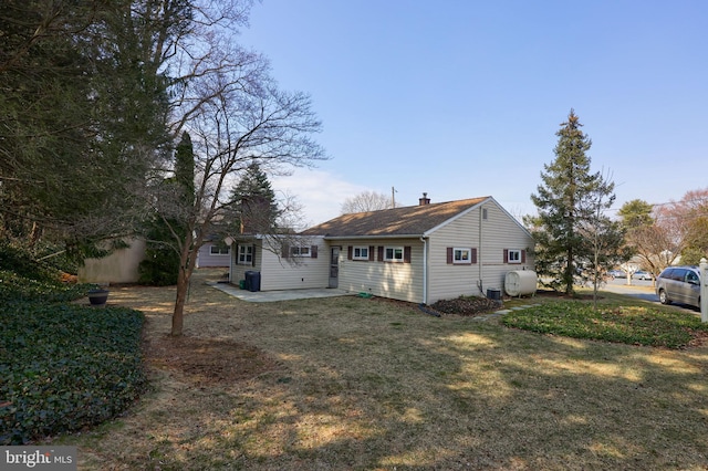 view of front of property featuring a front yard, a patio, a chimney, and heating fuel